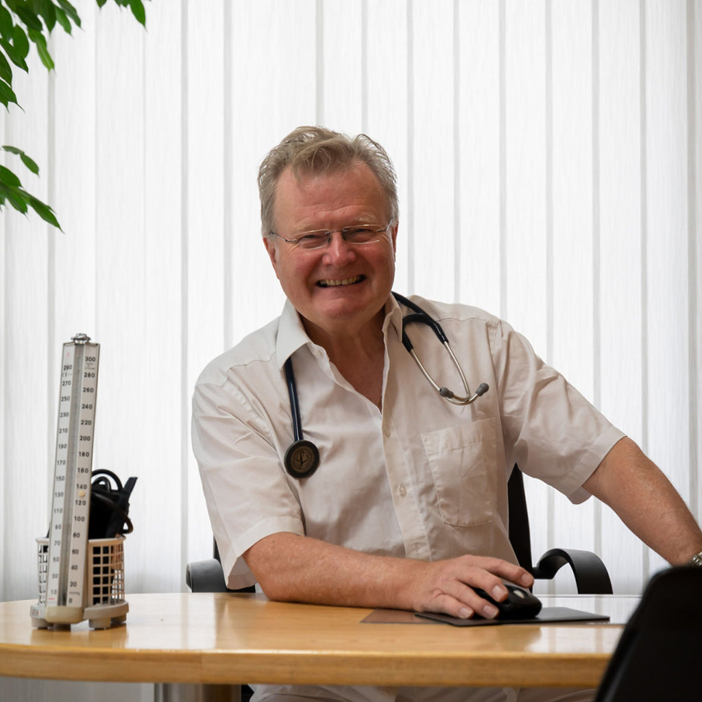 „Heinz Domke, Facharzt für Innere Medizin mit eigener Praxis seit 2008, lächelt am Schreibtisch in seiner Praxis. Er empfiehlt präventive Ansätze wie Nahrungsergänzung zur Unterstützung der Gesundheit bis ins hohe Alter.“